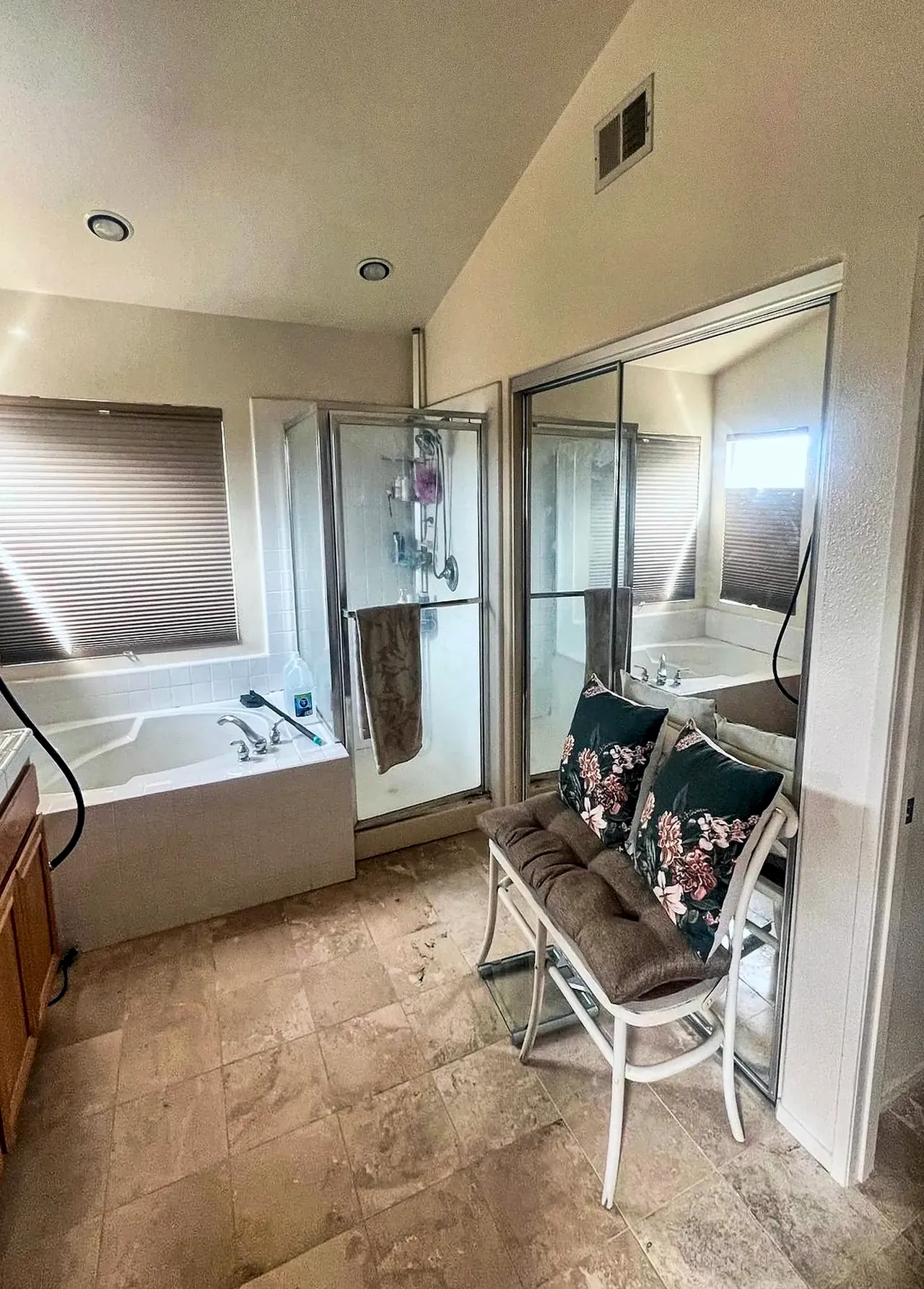 Primary bathroom before the remodel, with a drop-in tub in a tile deck under the window, a framed shower stall and a travertine-look floor
