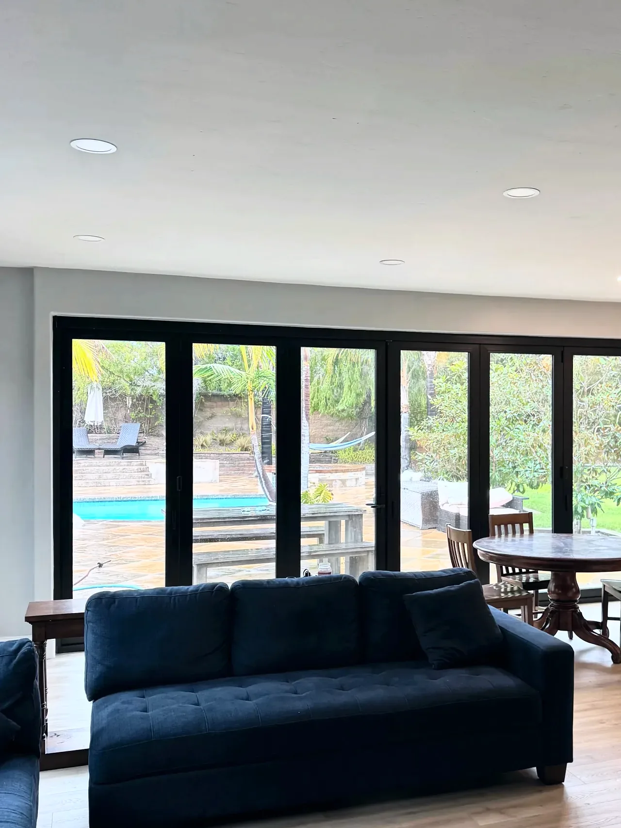 Carlsbad family room after, with a black bifold door opening to the patio and pool